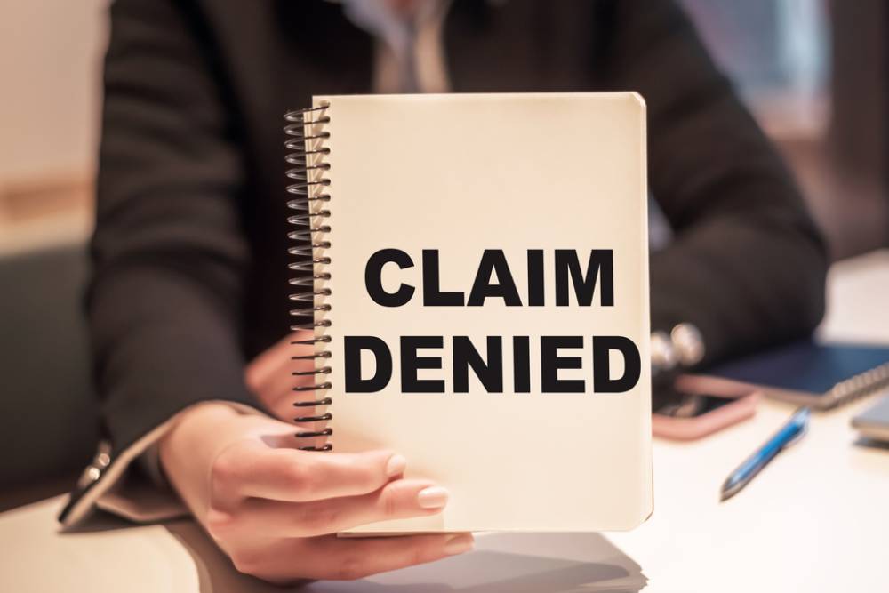 business woman holds a notebook with the text claim denied
